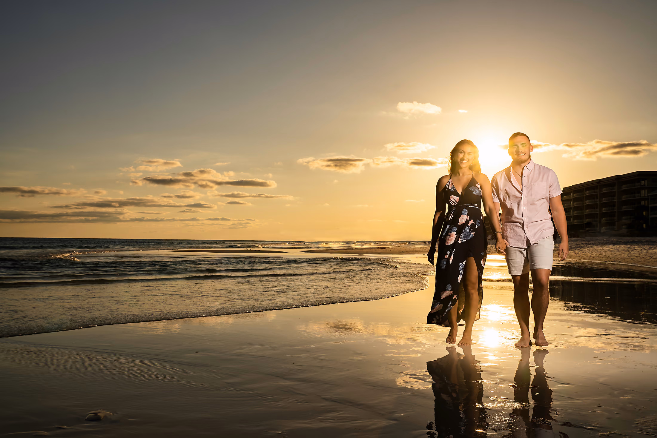 Couple walking hand in hand along the shoreline at sunset