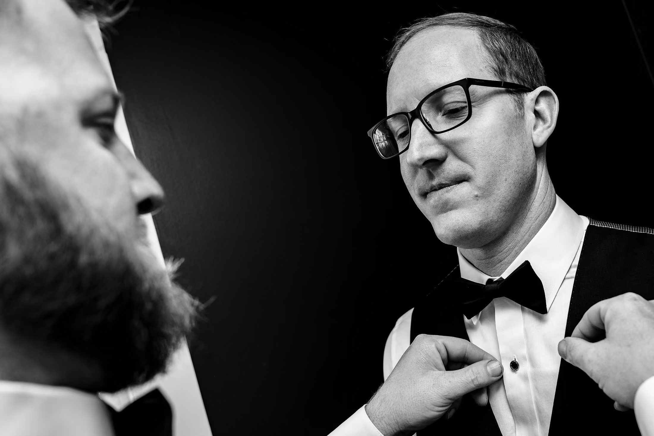 Black-and-white groom fixing his bow tie