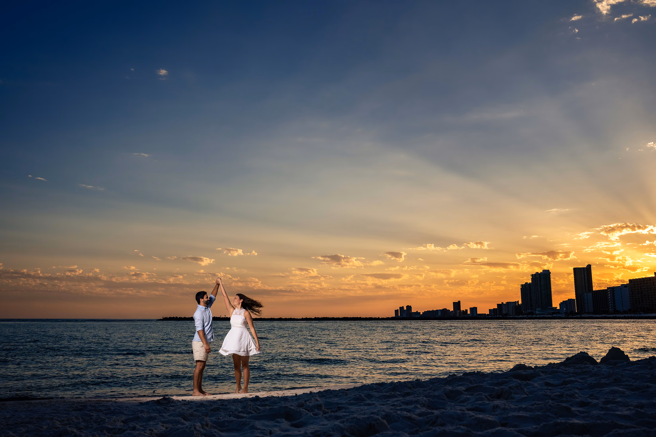Couple on the beach at sunset with the shoreline stretching behind