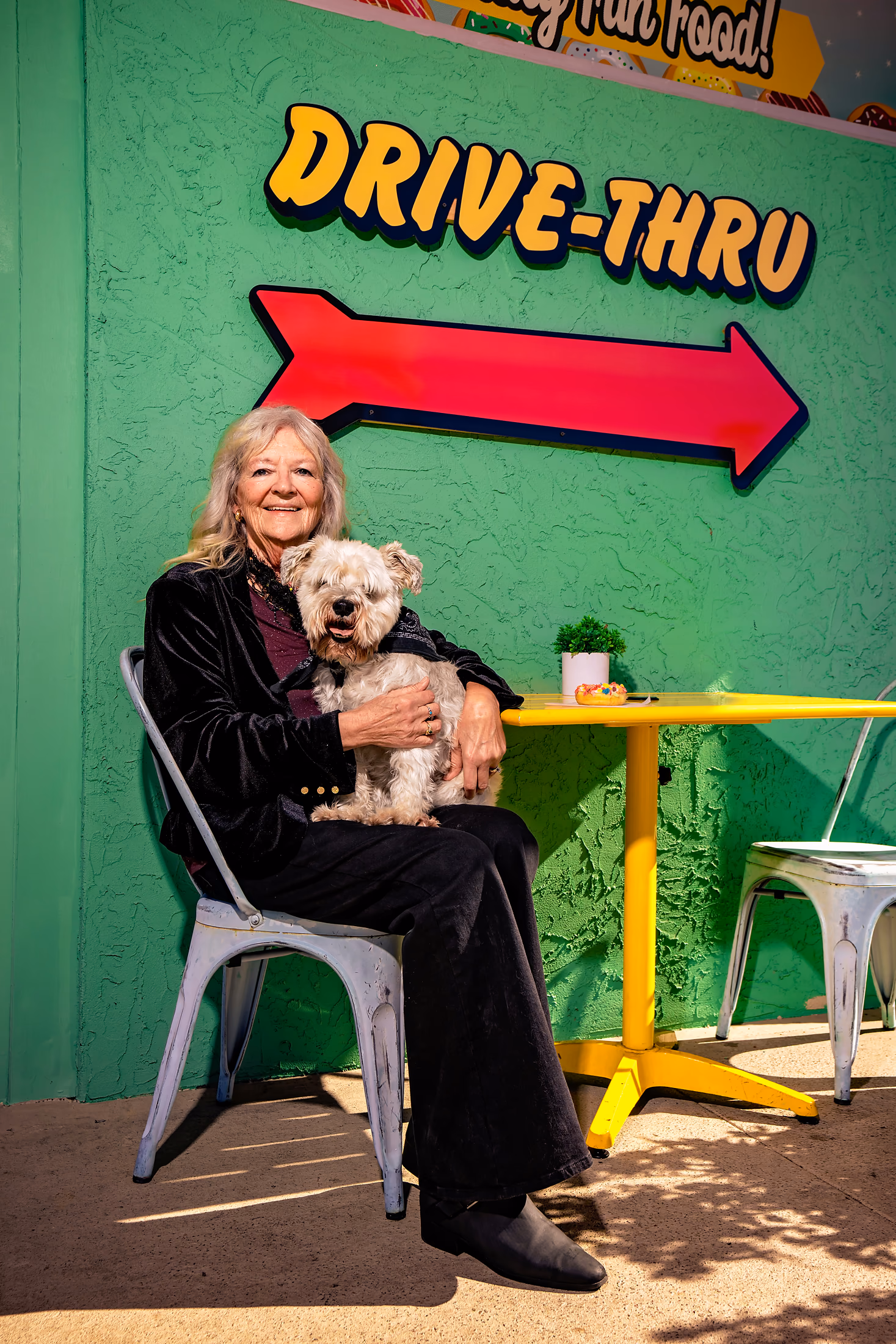 Woman holding her small dog in front of a colorful retro mural