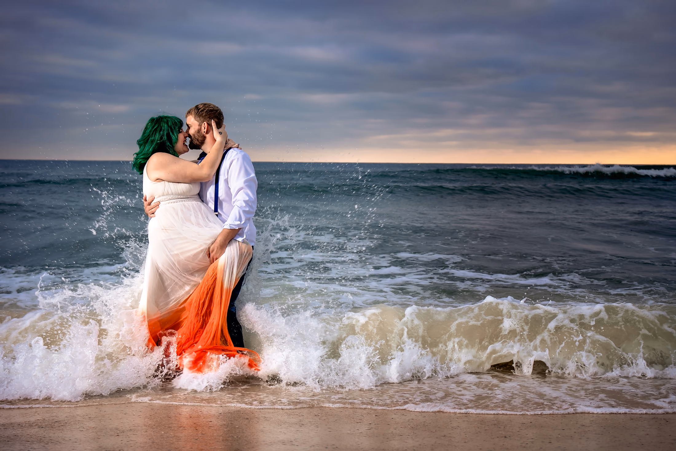 Groom lifting his bride for a kiss in the breaking surf