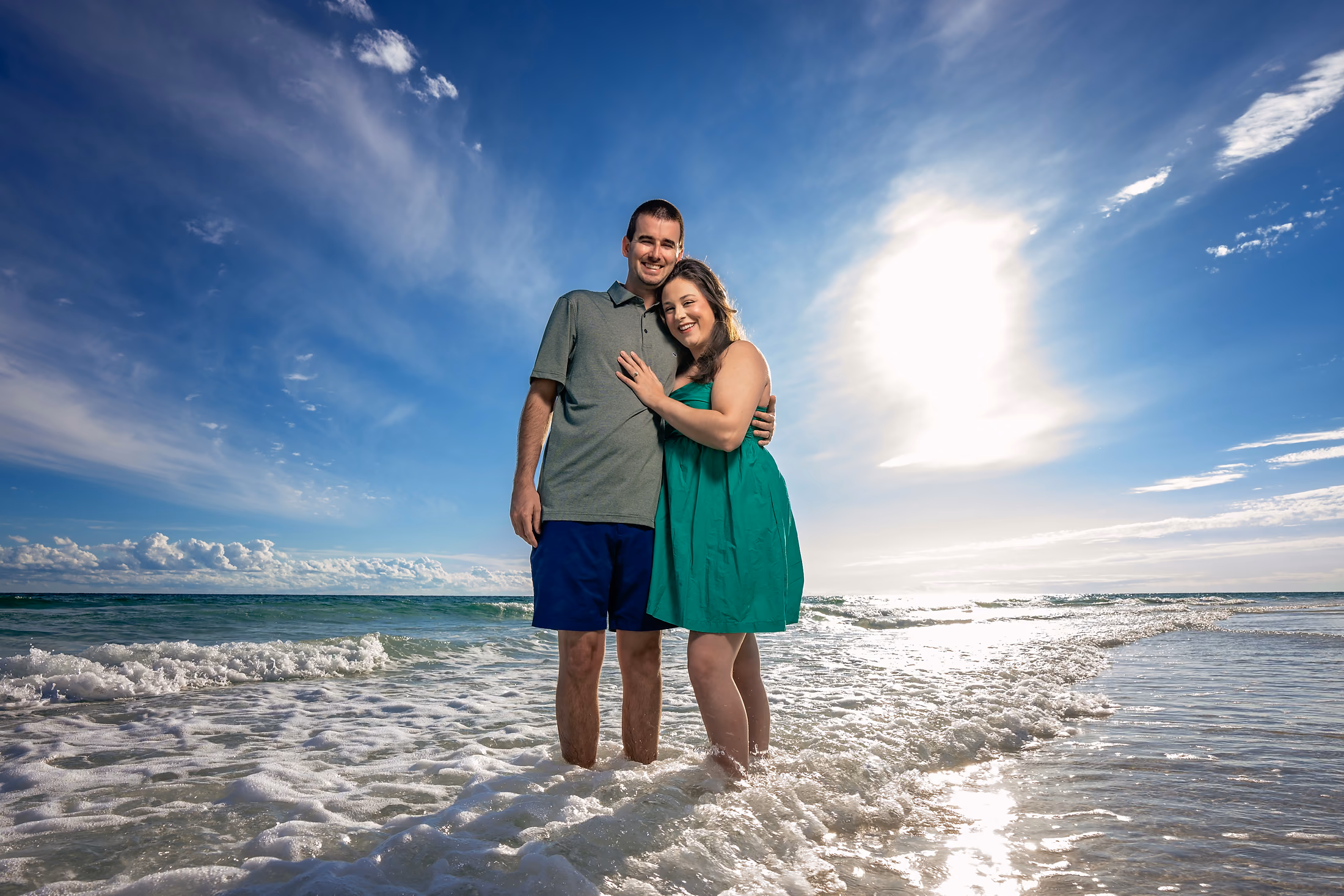 Couple embracing as sunlight breaks behind them on the beach