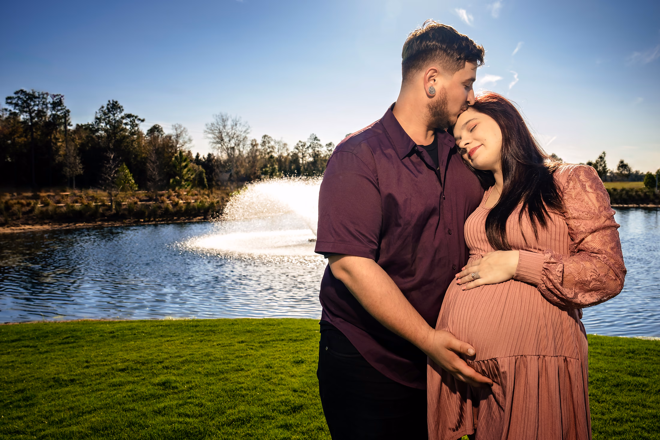 Expecting parents cradling the bump beside the water