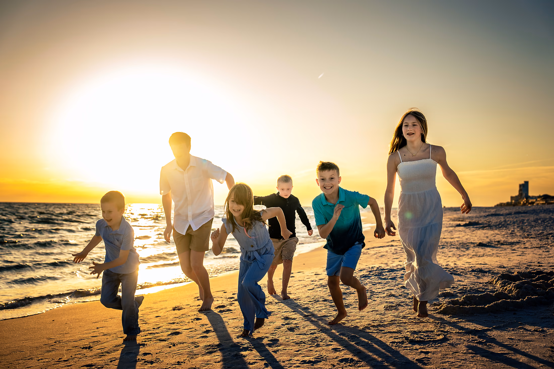 Family running along the beach into the setting sun