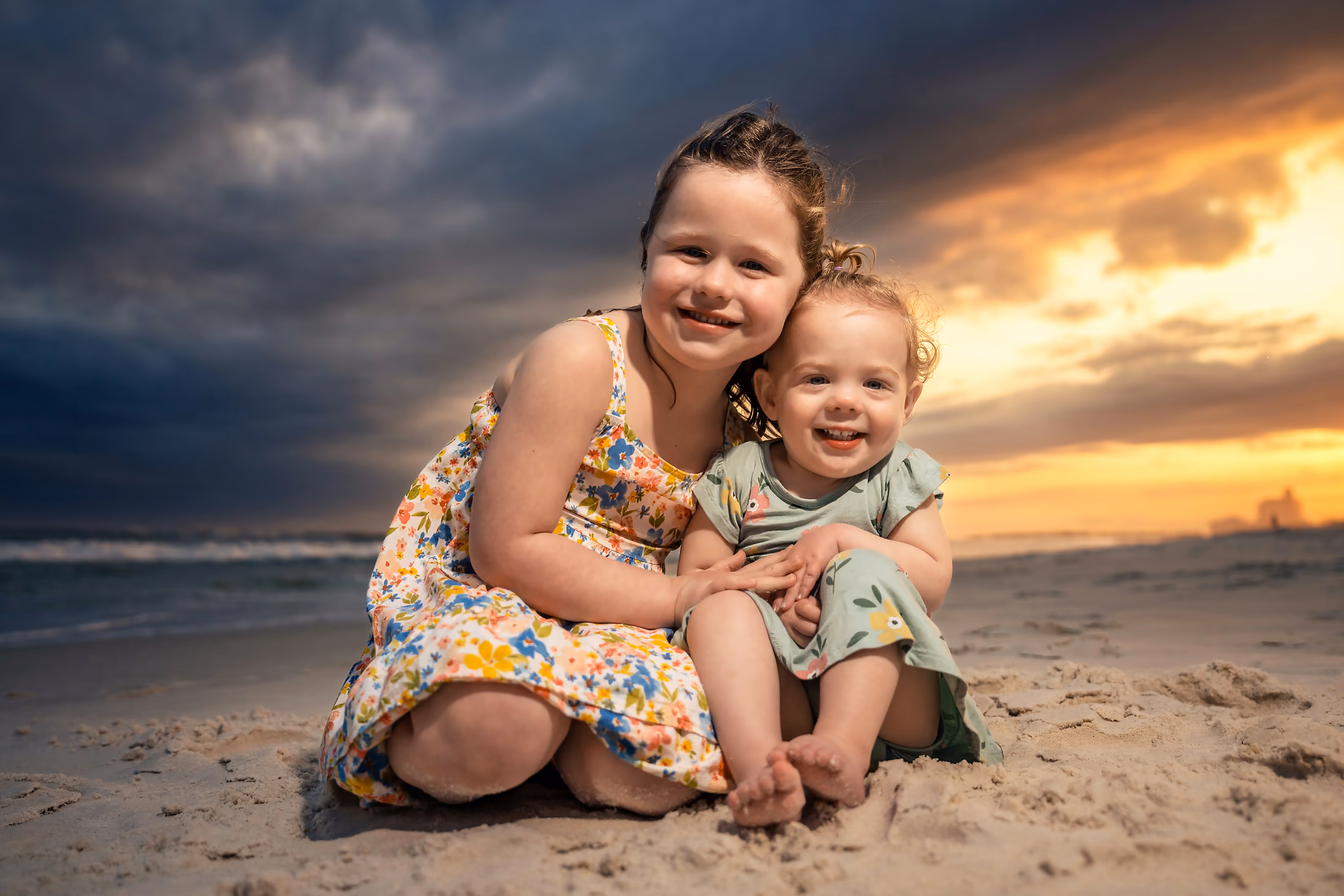 Two sisters hugging on the beach beneath gathering clouds