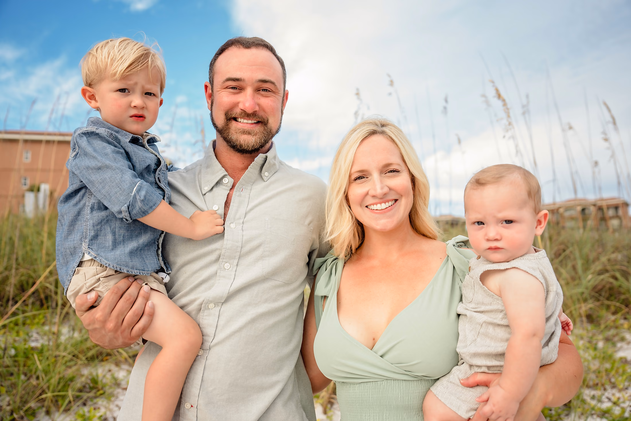 Parents holding their two little ones among the sea oats