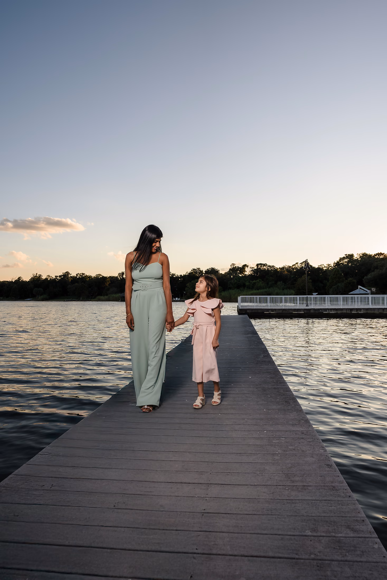 Woman in a flowing dress on a quiet dock at dusk