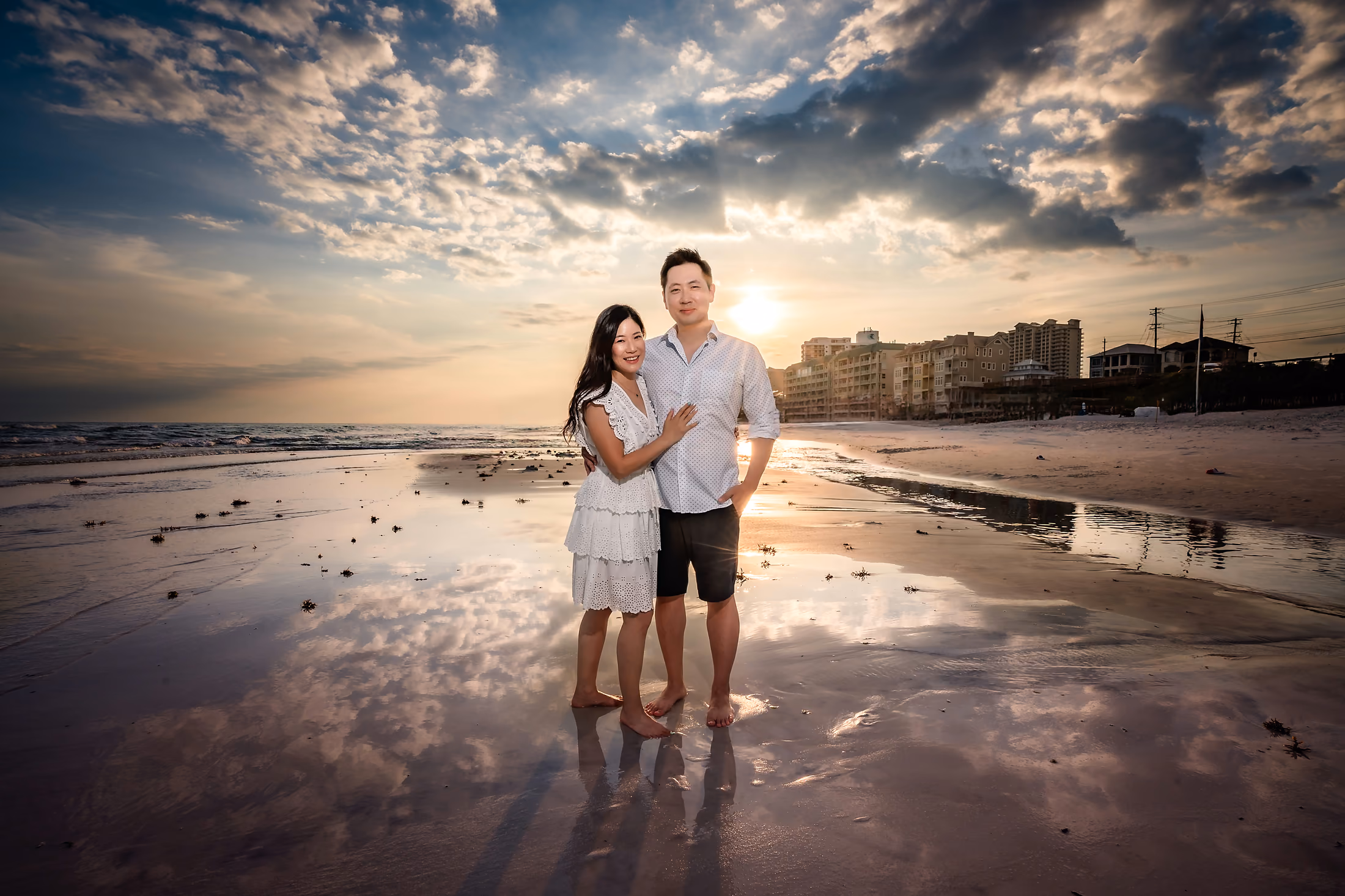 Family reflected on the wet sand at sunset