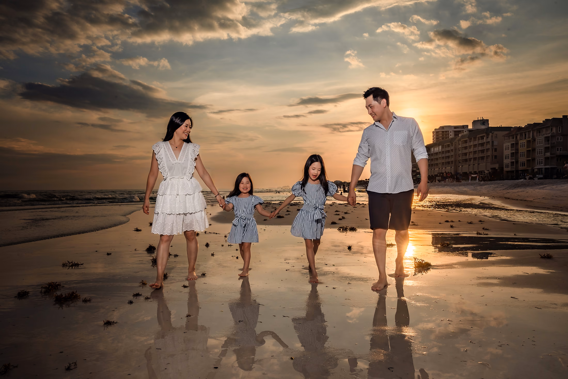 Family walking the water's edge as the sun sets