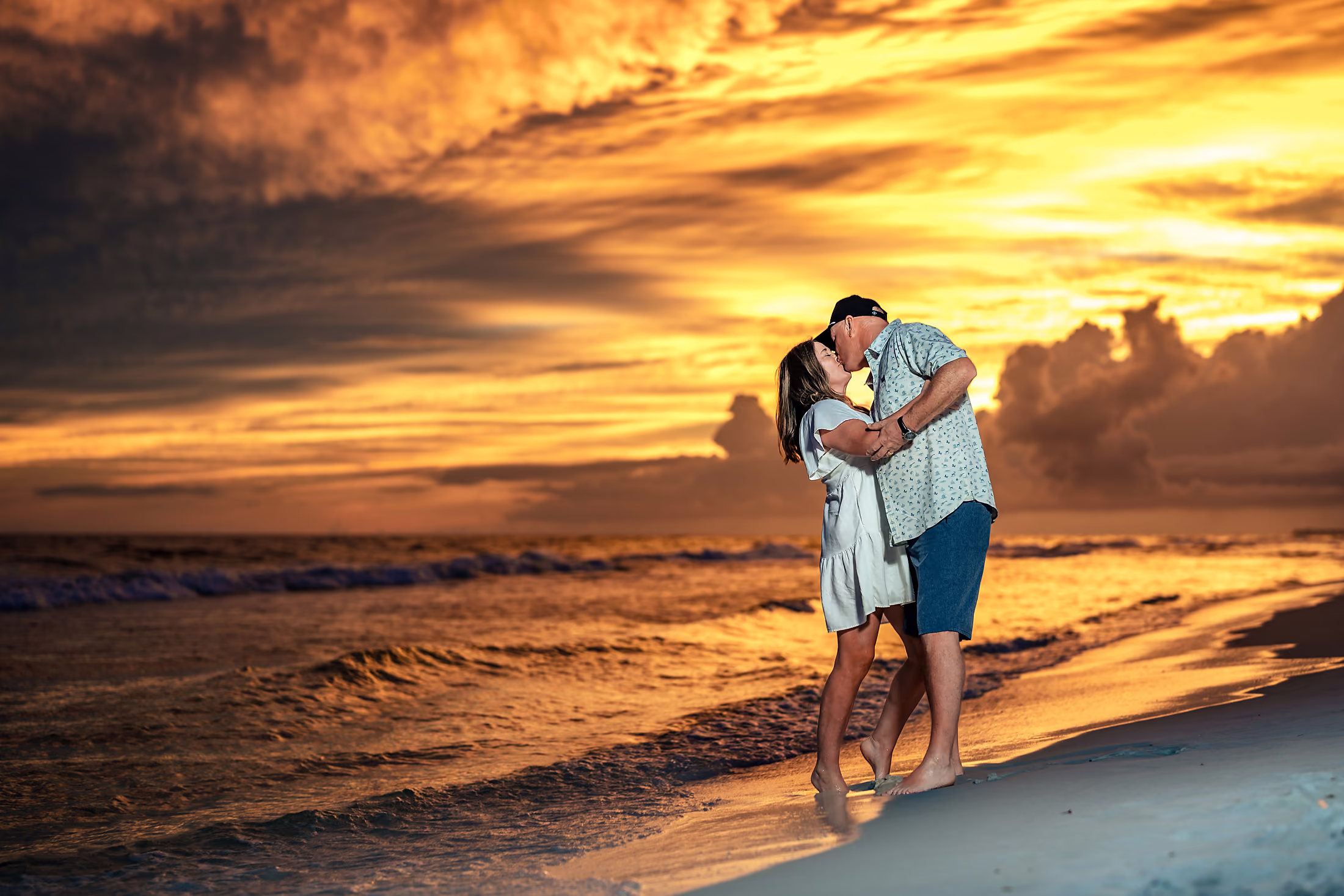 Couple kissing against a fiery orange sky on the beach