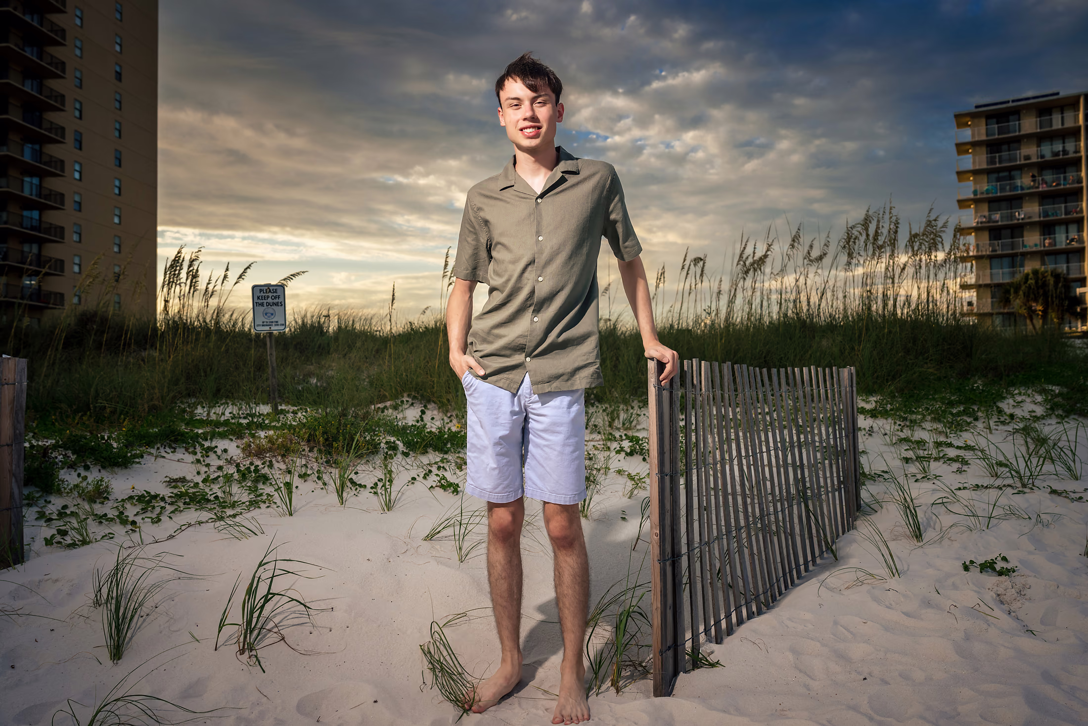 Man leaning against the dune fence in the evening light