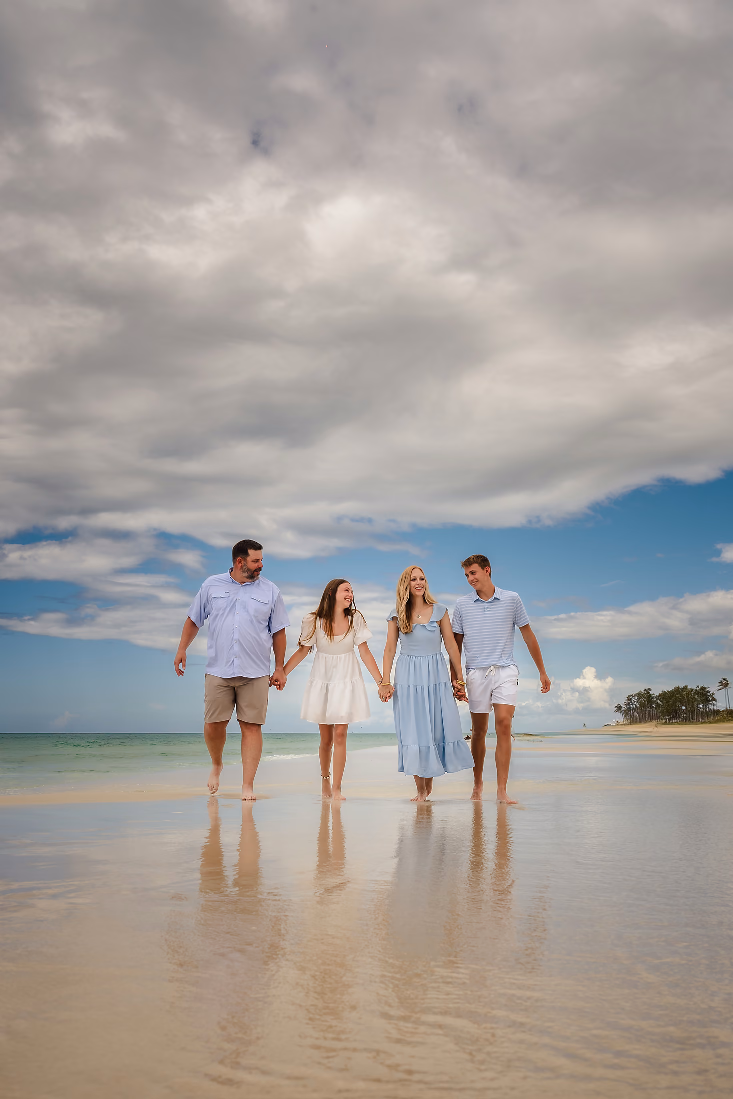Family in white walking the shoreline at dusk