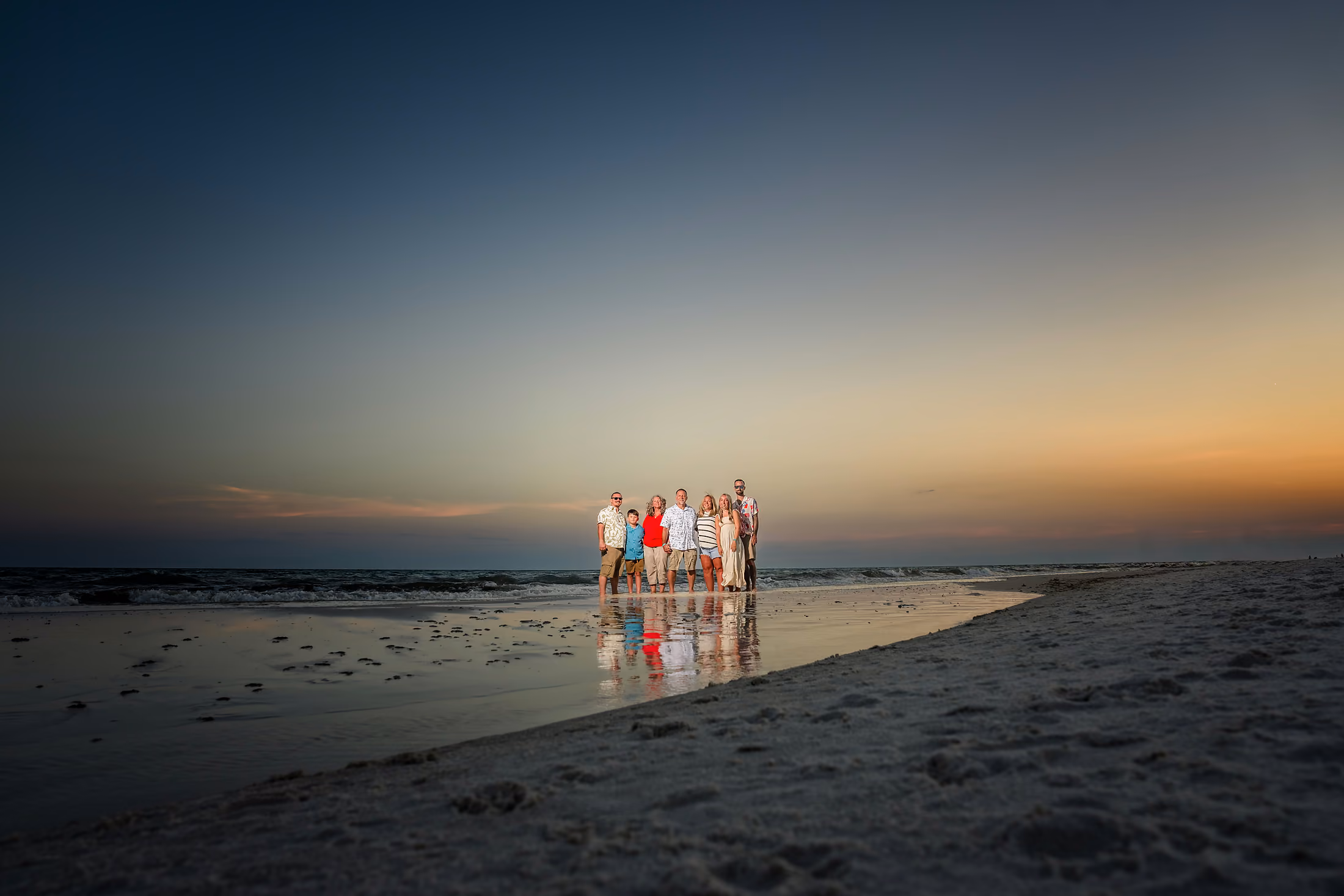 Lone family far down the shoreline at sunset