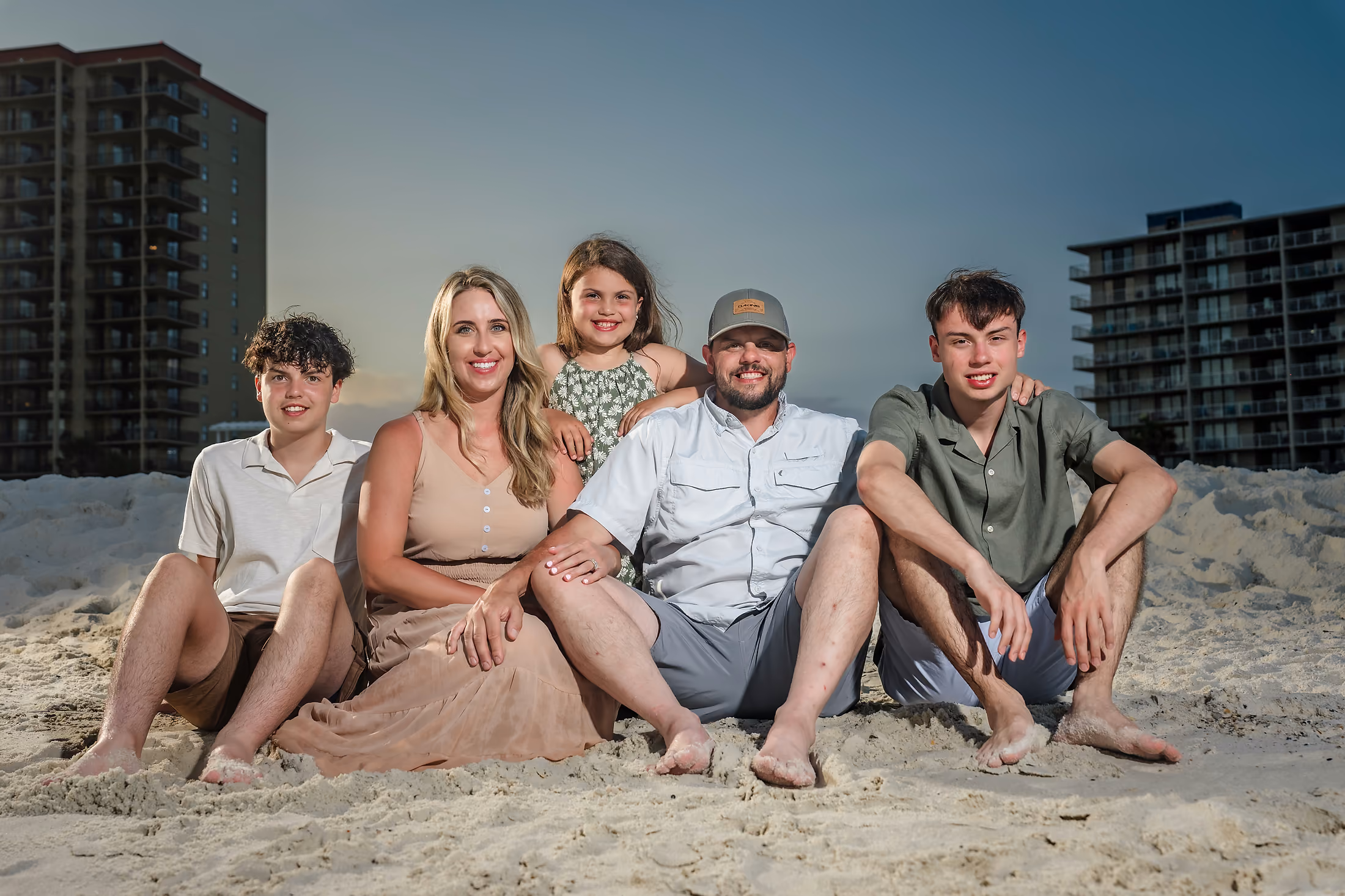 Family sitting together in the sand at sunset