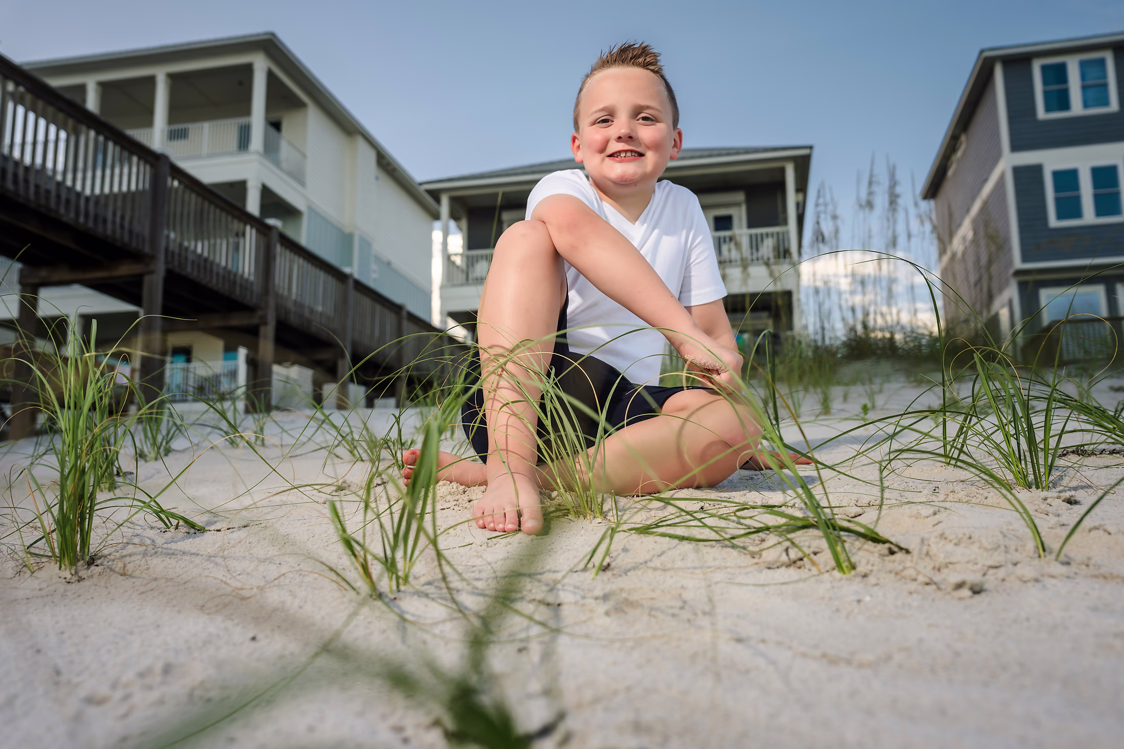 Young boy sitting in the dune grasses