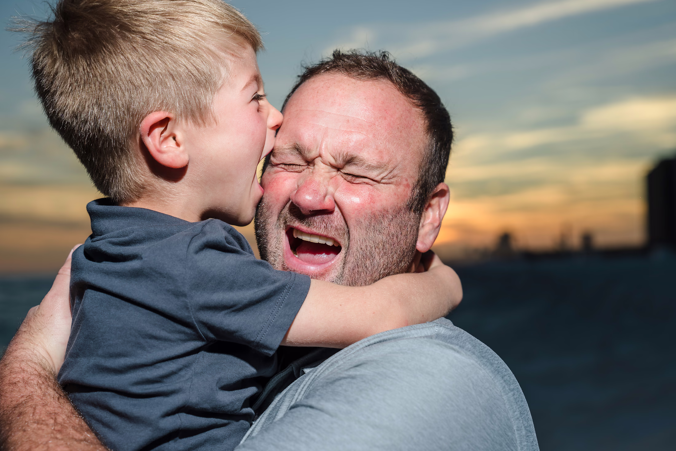 Son kissing his father's cheek at sunset
