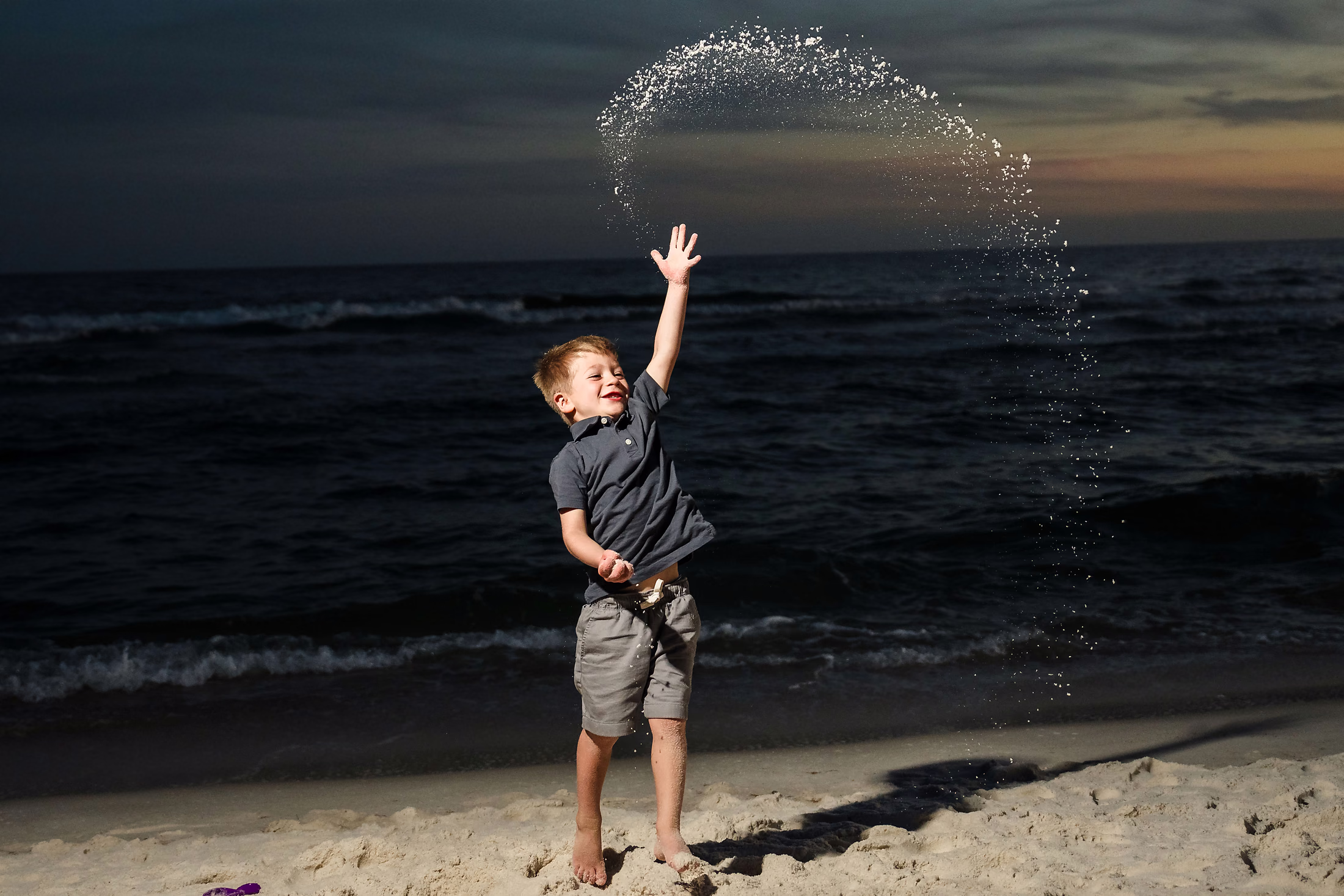 Boy tossing water into the air at sunset