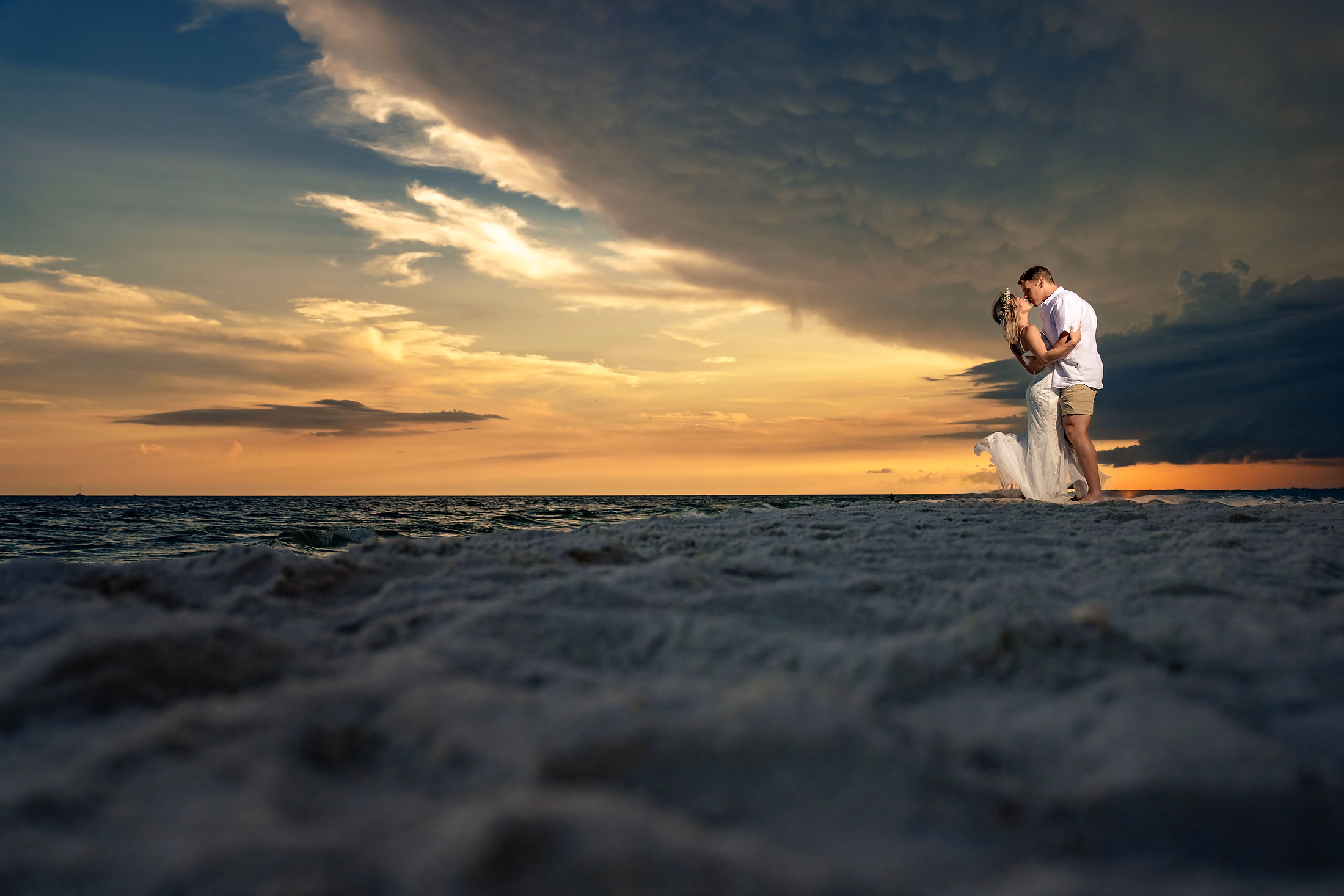 Couple on the beach beneath dramatic clouds