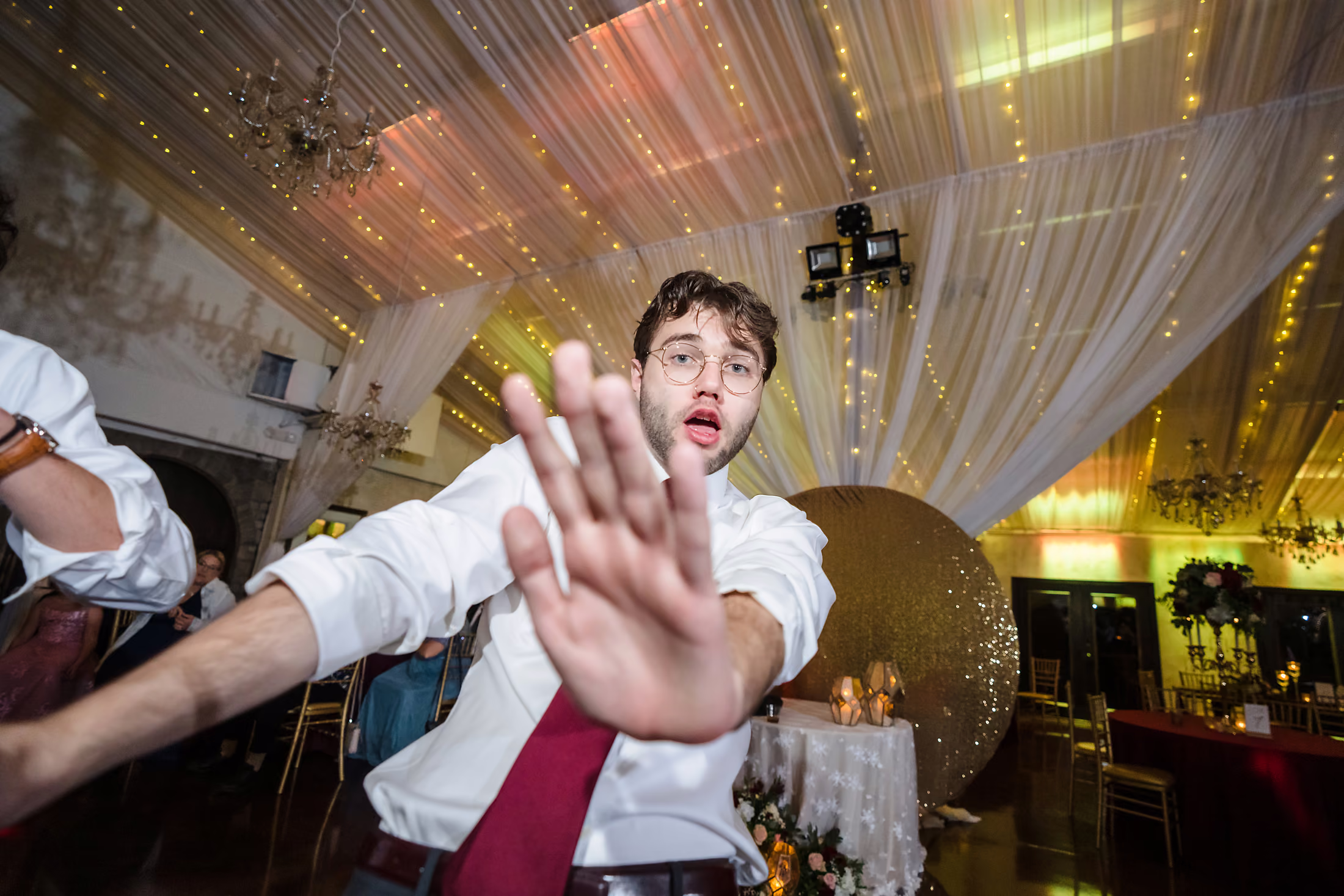 Groom reaching out beneath the draped tent