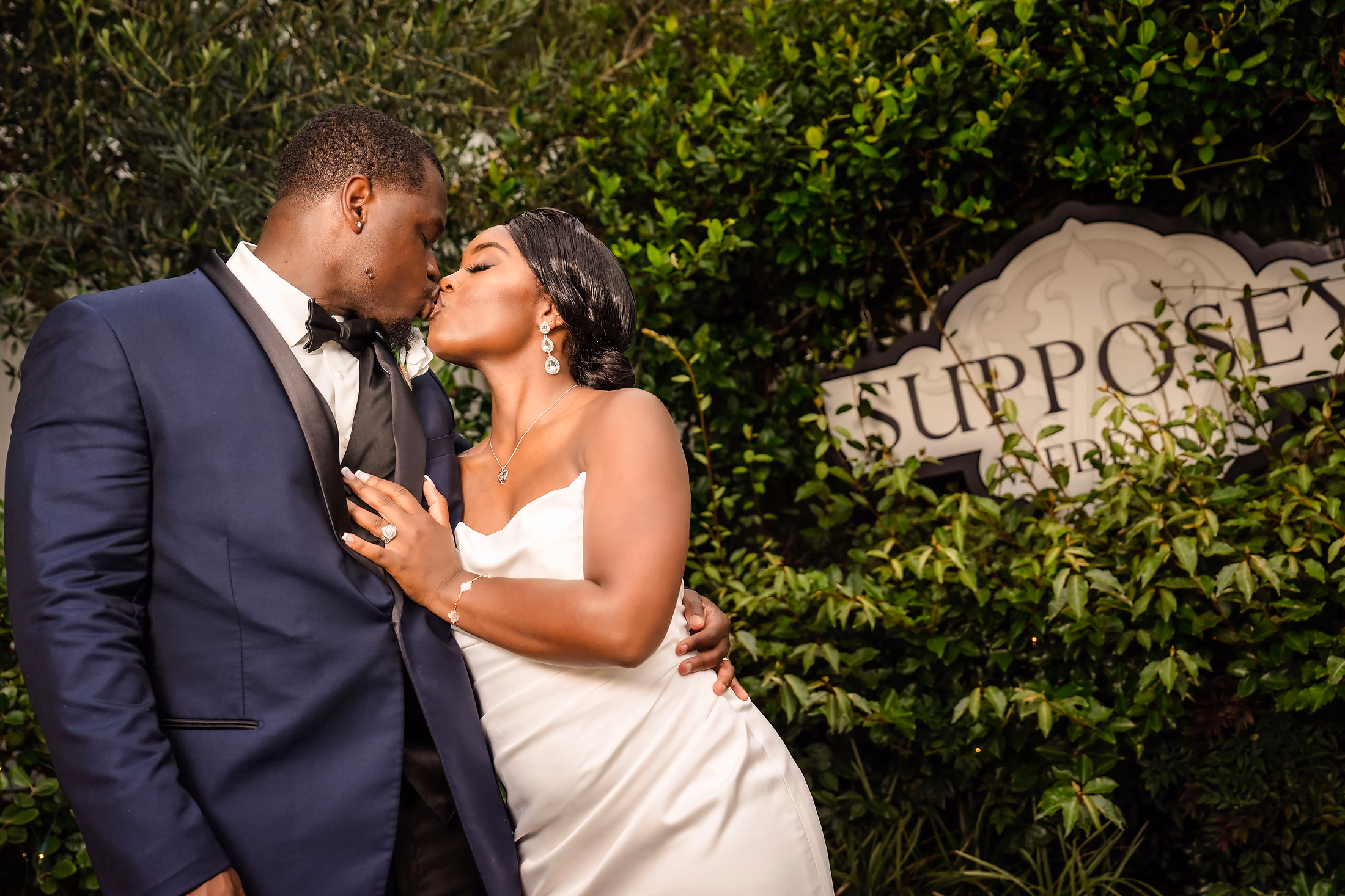 Groom kissing his bride amid the greenery