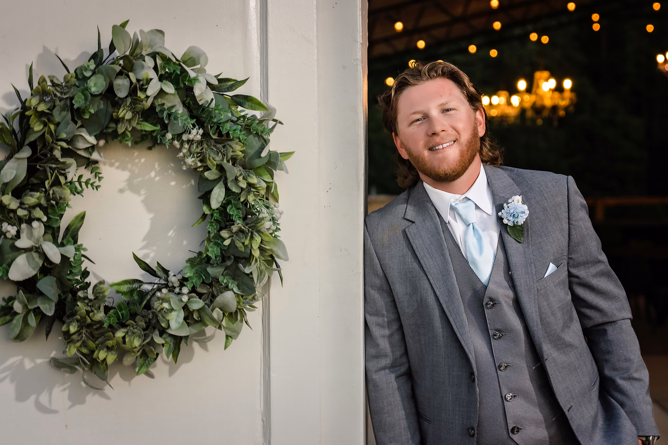 Groom beside a circular greenery wreath