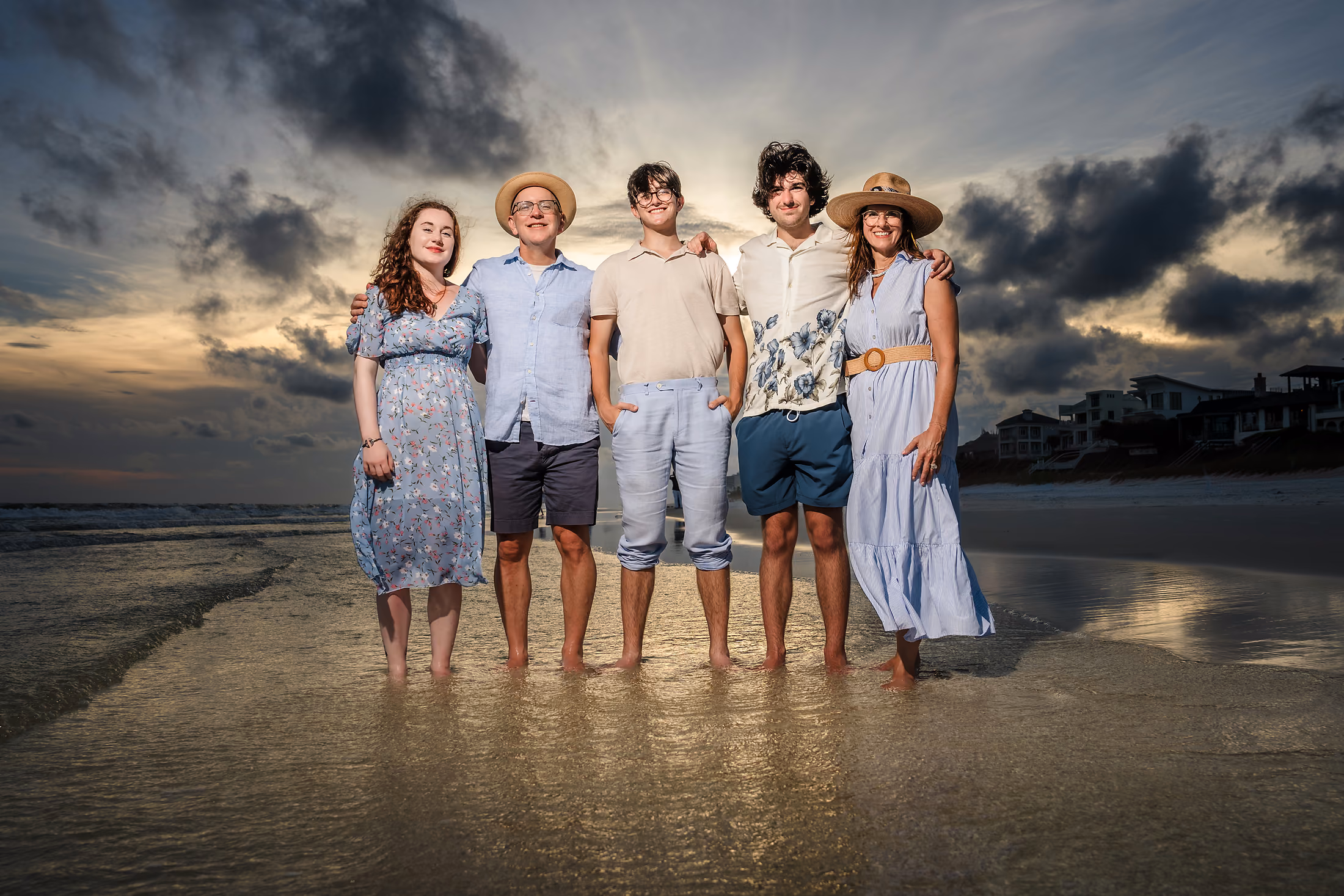 Family on the reflective sand beneath a brooding sunset