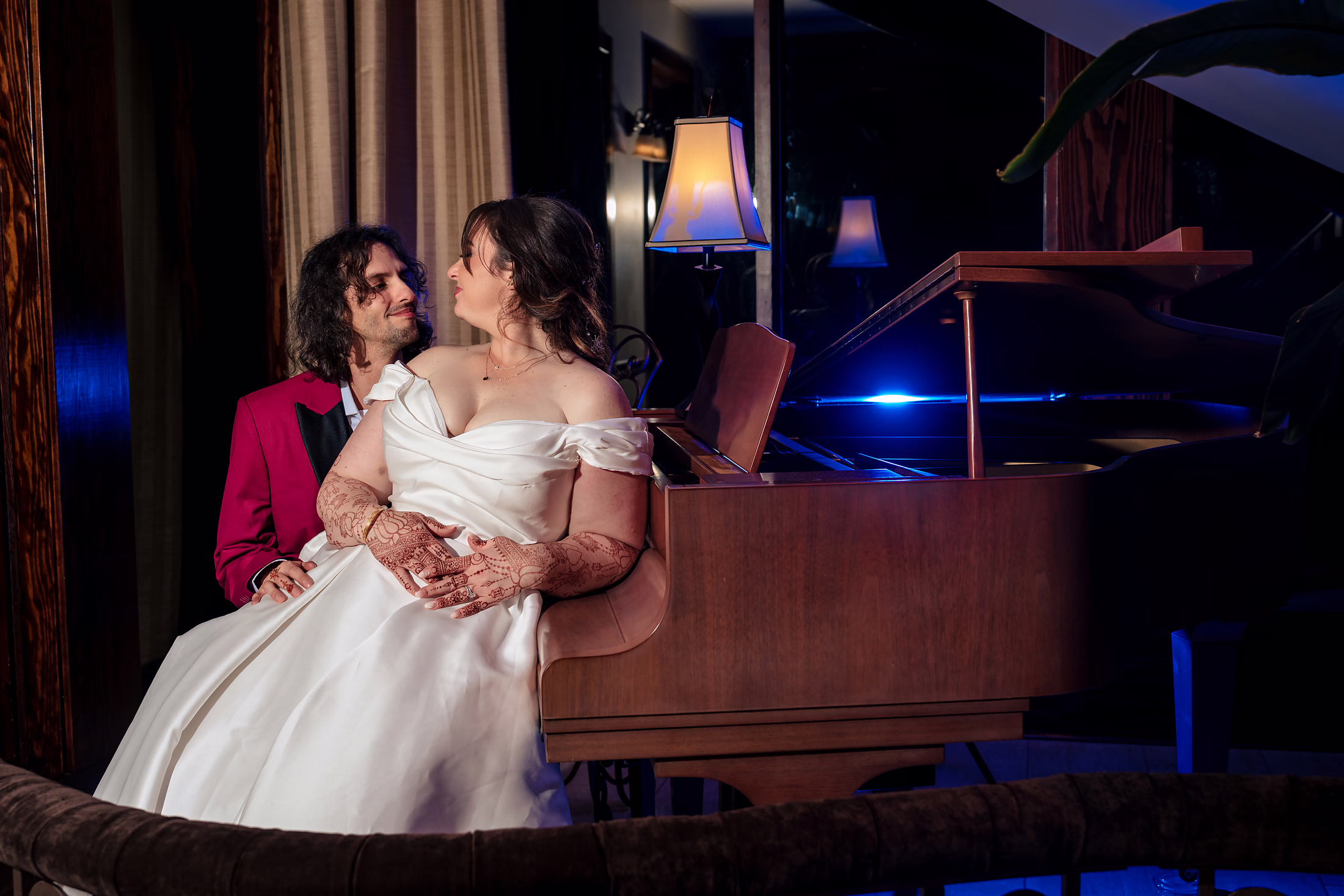 Bride sharing a laugh at the piano in warm window light