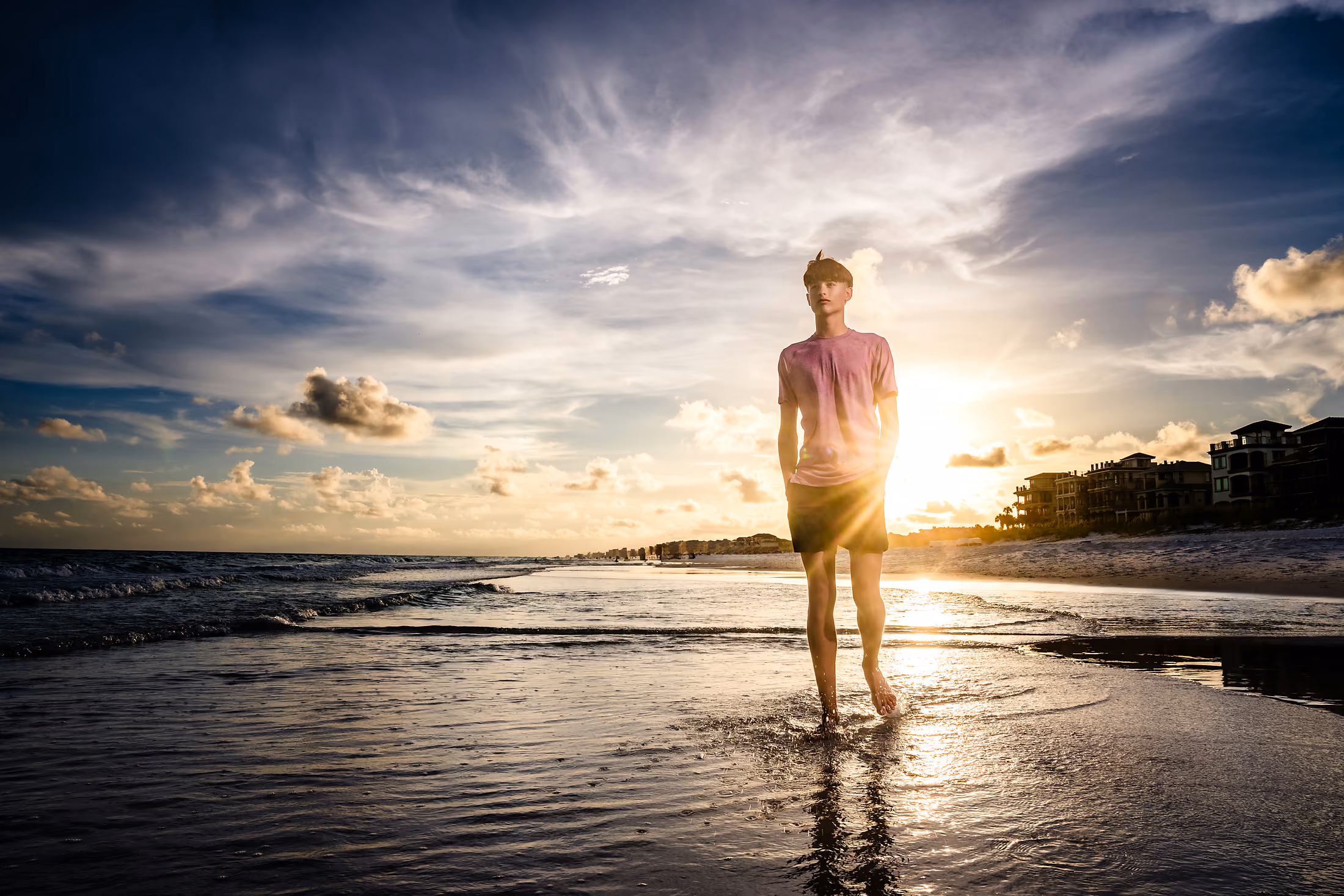 Teenage boy on the reflective sand at sunset