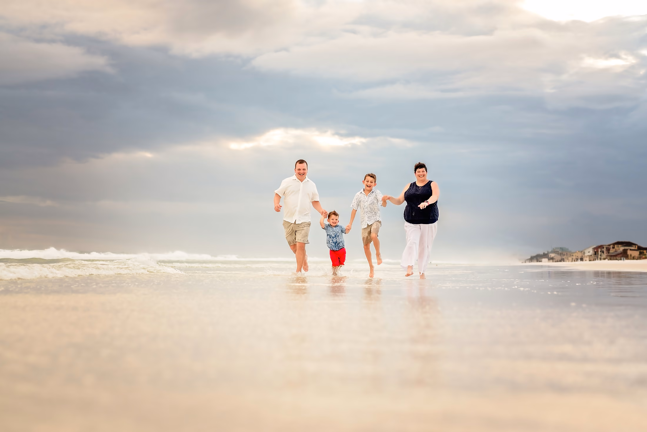 Parents swinging their child between them down the beach