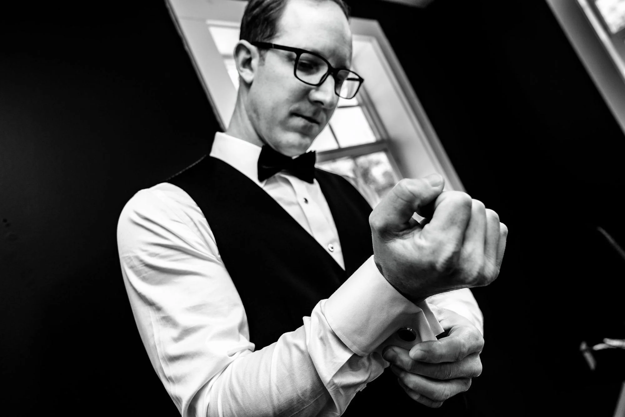 Black-and-white groom fastening his cuff
