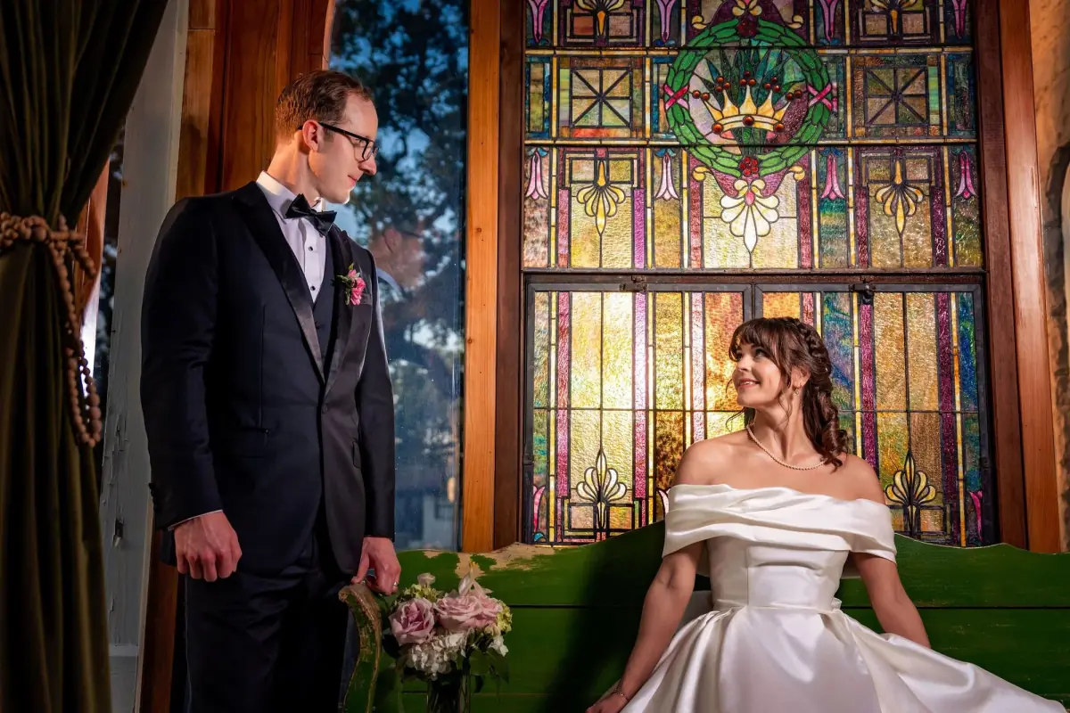 Groom standing with his bride at the stained glass