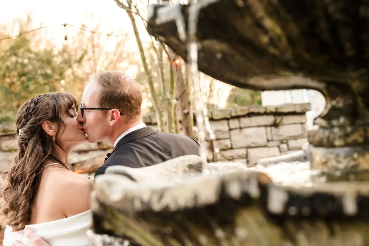 Couple kissing across a low stone wall