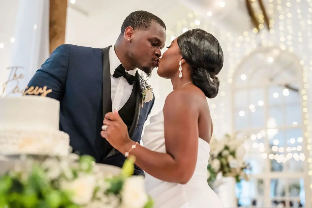 Couple kissing under string lights at the white venue