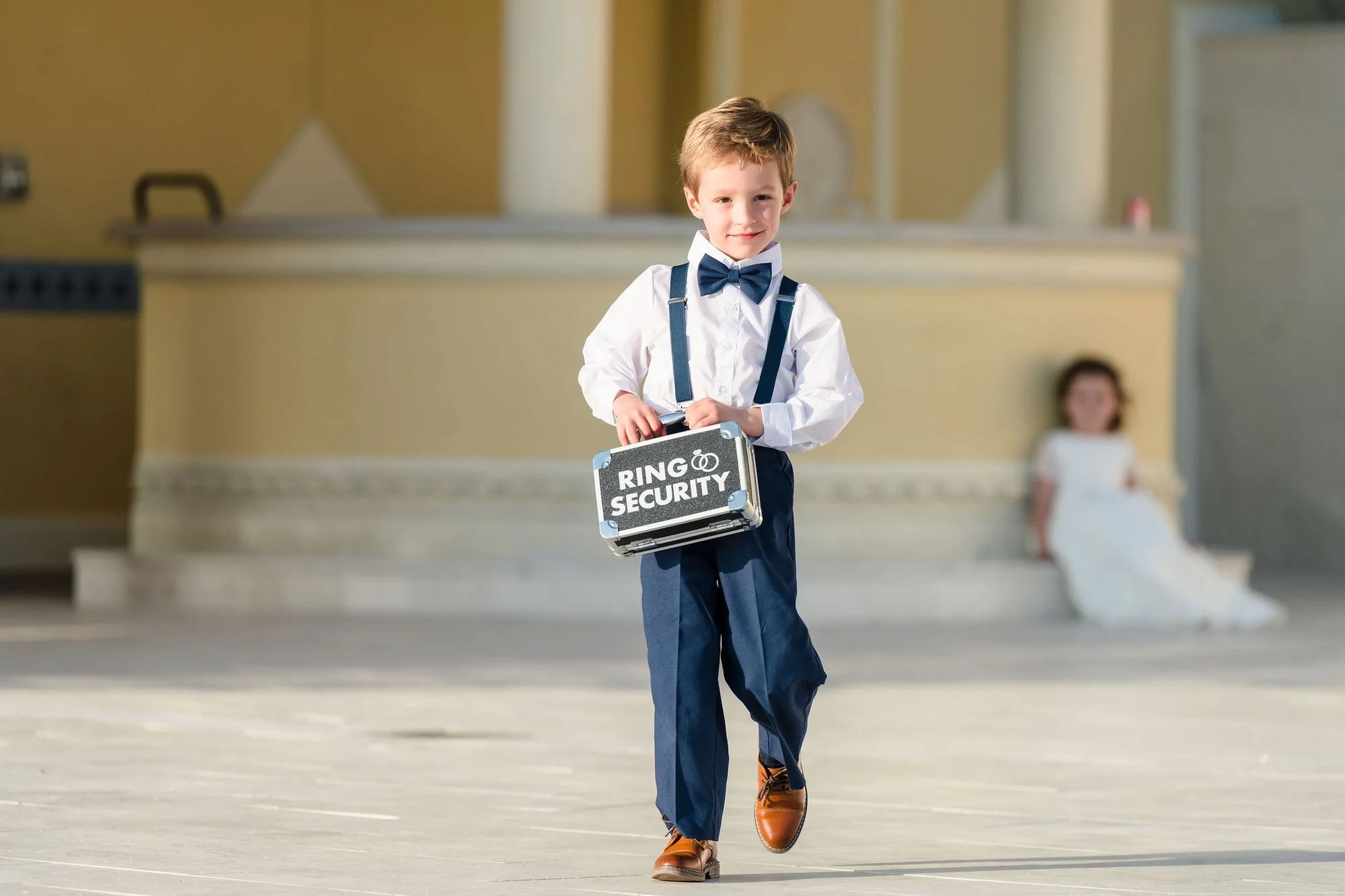 Young ring bearer with his sign by the columns