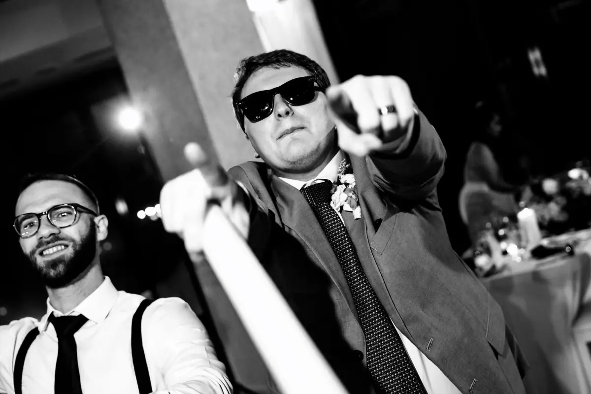 Black-and-white groom in suspenders at the party