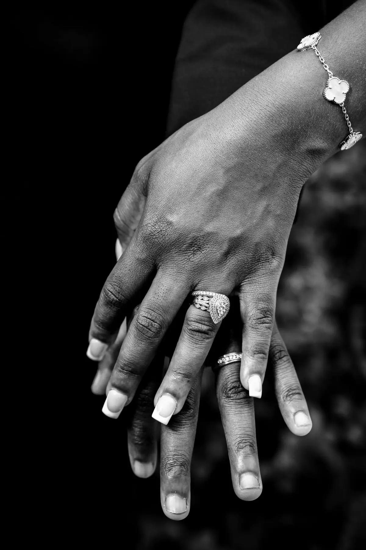 Black-and-white close-up of two ringed hands