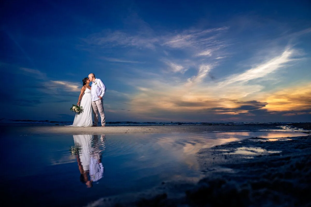 Bride reflected at the water edge at sunset