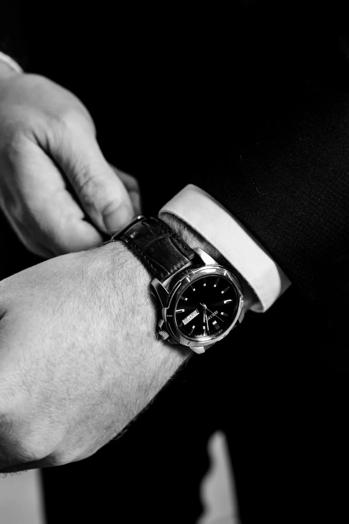 Black-and-white groom fastening his watch