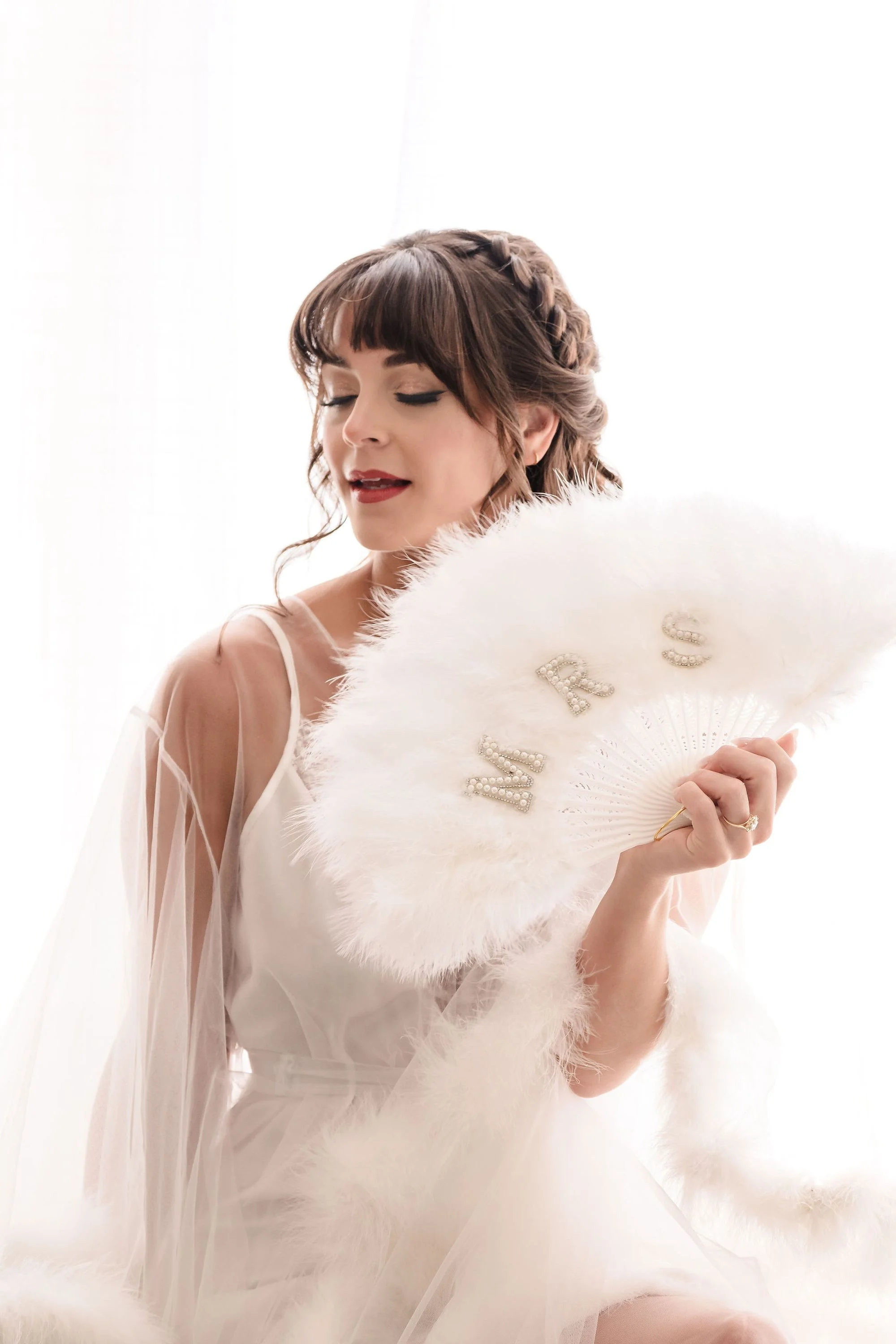 Bride wrapped in a soft fur stole, eyes lowered in quiet light