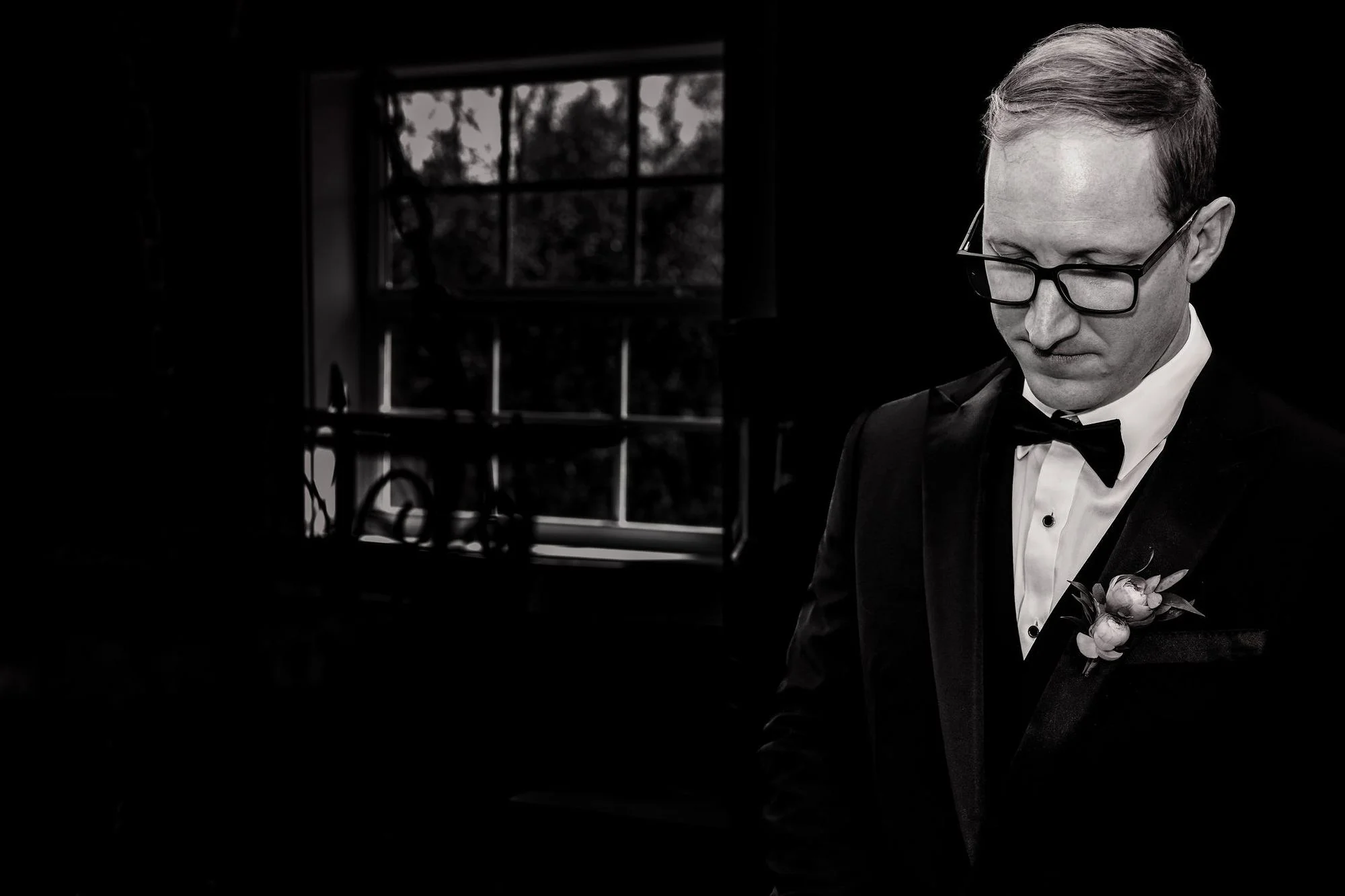 Portrait of the groom in low, dramatic window light
