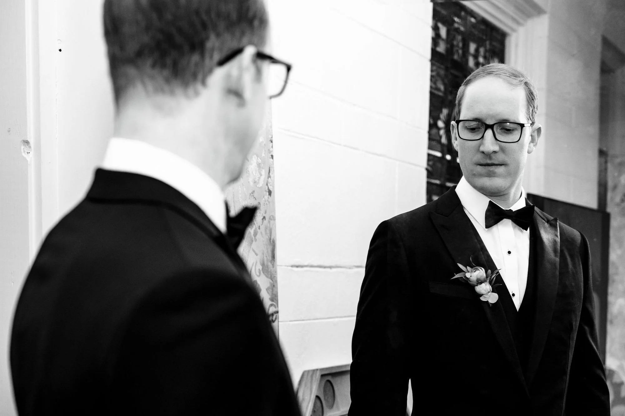 Two men in dark suits face each other before the ceremony