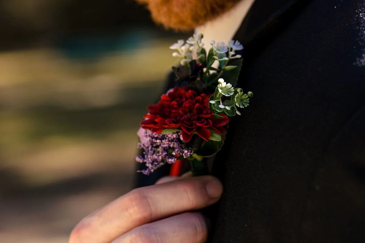 Boutonniere of deep red blooms pinned to the lapel