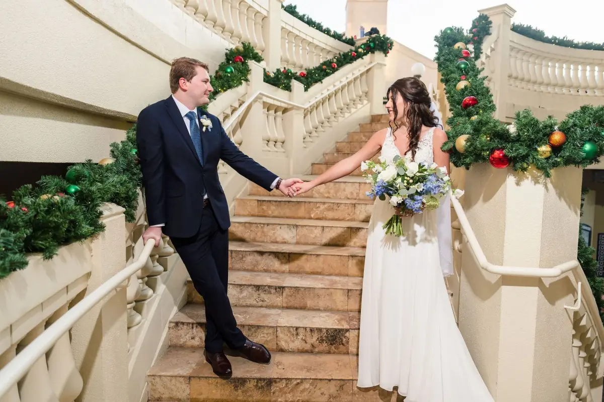 Bride and groom descend a grand staircase laced with greenery