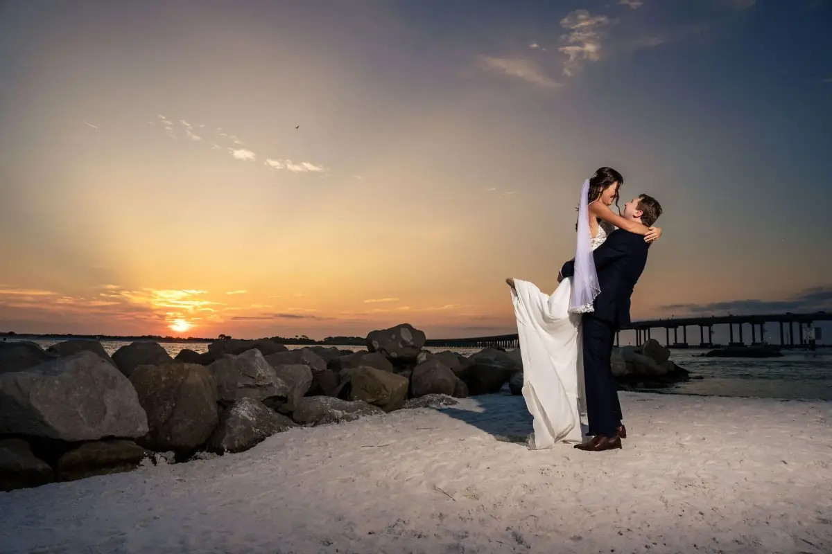 Bride and groom on the sand as the sun sinks low