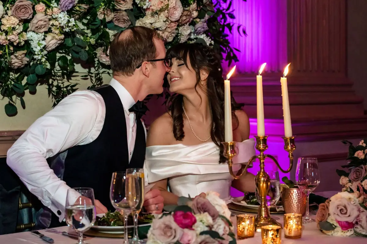 A kiss across the table under amethyst light