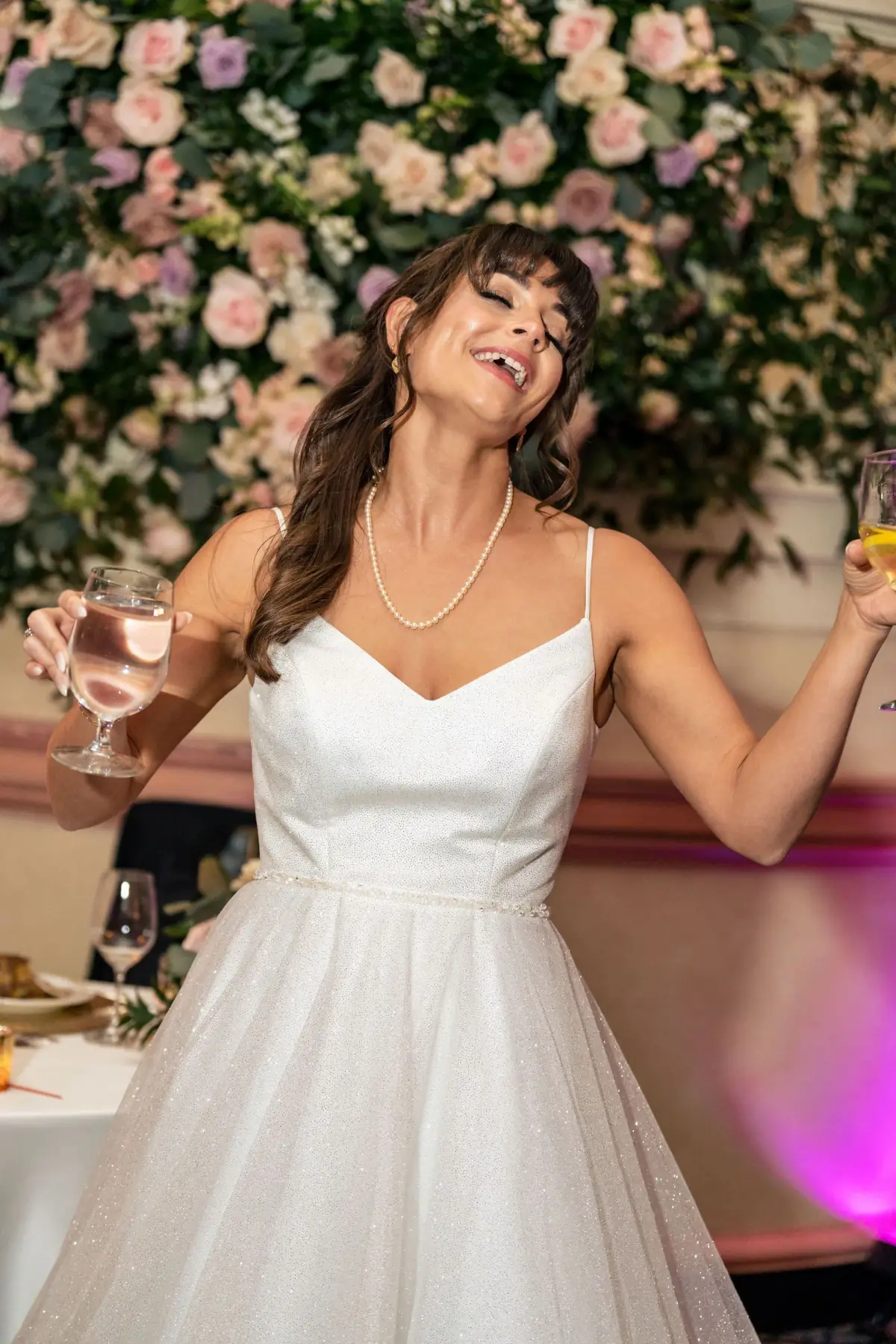 Bride poses before a lush flower wall