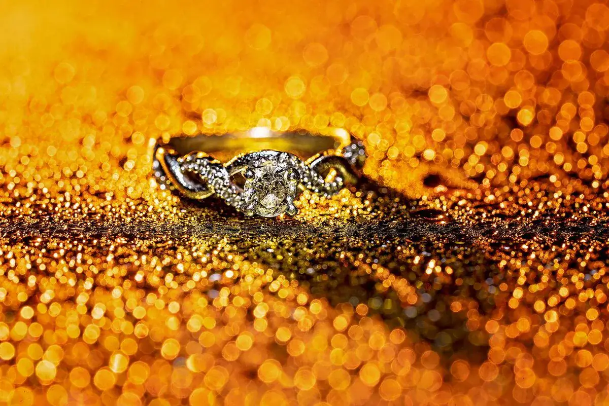 The wedding ring rests on a bed of golden sparkle