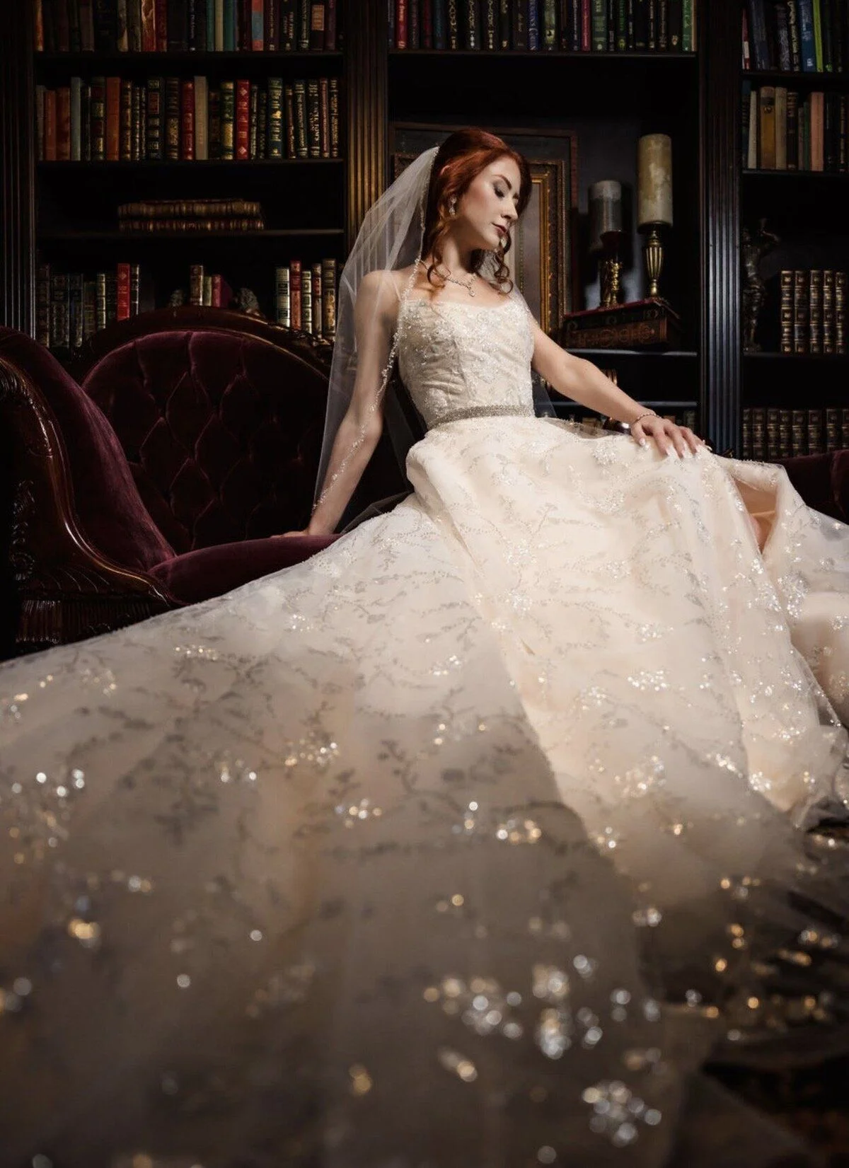Bride seated among library shelves, gown sweeping the floor