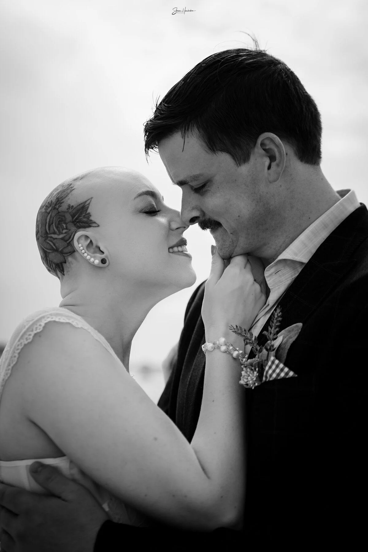 A soft black-and-white kiss, foreheads resting together