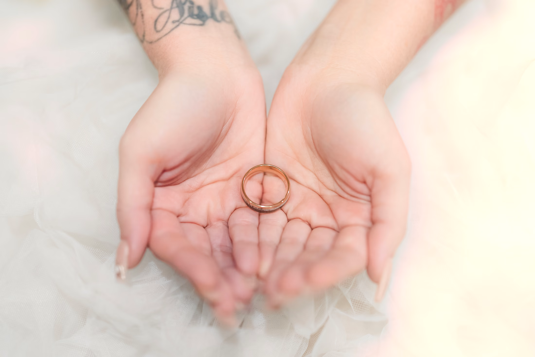 Wedding ring cradled in two hands full of beach sand